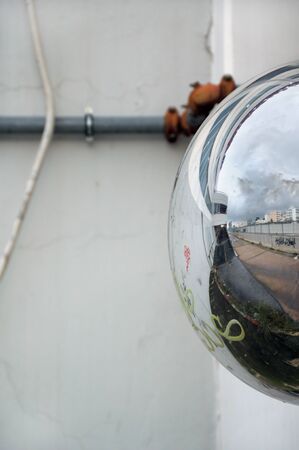 View of cityscape reflected on convex parking mirror. Abstract background.の写真素材