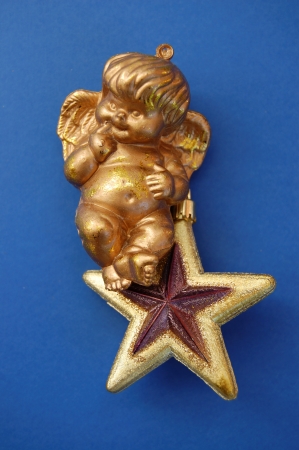 Little angel sitting on golden christmas star bauble. Seasonal decoration.の写真素材