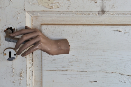 Doll hand opening a closed door in haunted house.の写真素材