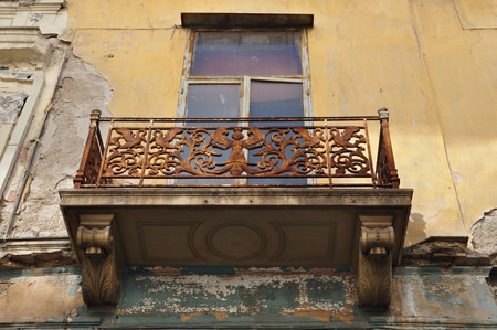Winged female figure rusty floral pattern and swans on balcony balustrade of abandoned neoclassical house  Athens Greece の写真素材