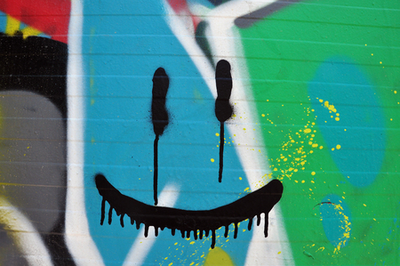 Abstract smiling face on wall with colorful graffiti and splashed paint.の写真素材