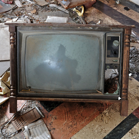 Vintage tv set with wooden frame. Broken television on the dirty floor of an abandoned house.の写真素材