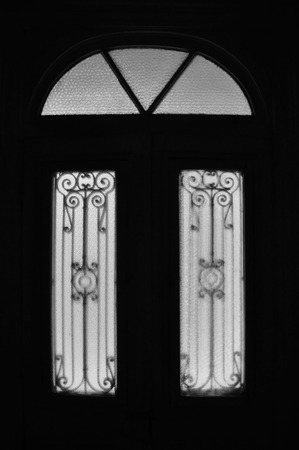 Vintage door frame with decorative motif and arched glass lite. Abandoned neoclassical house dark...