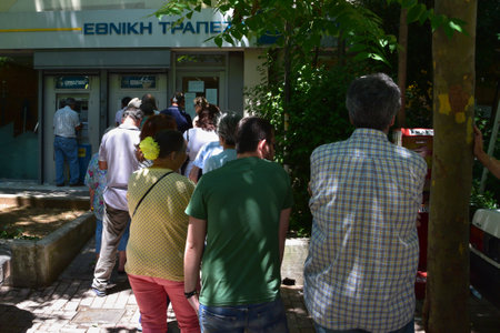 ATHENS, GREECE - JULY 1, 2015: Line of people waiting to withdraw cash money from ATM machine cashpoint. Banks are closed and daily limit capital controls are implemented. First day after Greece defaults on IMF loan payment.のeditorial素材