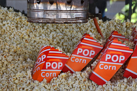 Pile of fresh popcorn and portions in bags made by antique hot air popper machine. Salty snack.の写真素材