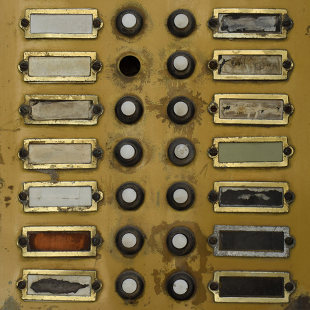 Rusty door bell with broken buttons and name plates. Vintage doorbell buzzer grungy background.