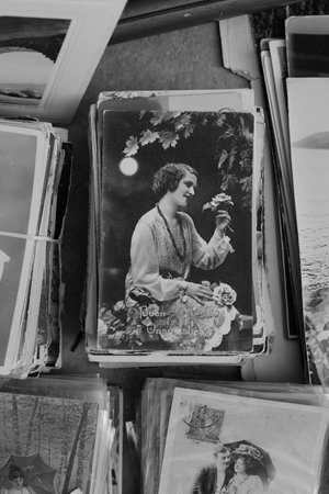 ATHENS, GREECE - SEPTEMBER 14, 2018: Vintage postcard of young woman with roses under moonlight and old photographs for sale at antiques store. Black and white.のeditorial素材