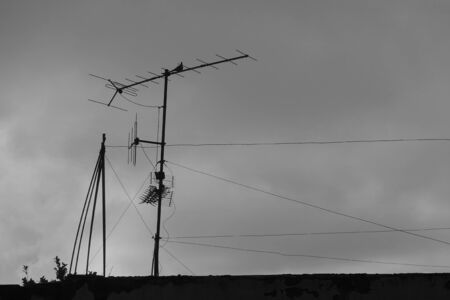 Old television antenna wires and bird on the roof of an abandoned house. Black and white.の写真素材