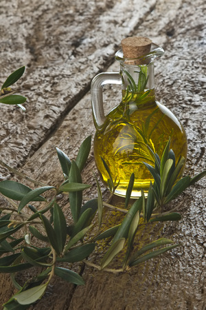 Extra virgin olive oil flavored with fresh rosemary on a old wooden tableの写真素材