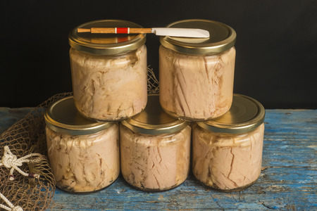 Tuna canned in glass jars with olive oil on blue rustic table, albacore Cantabrian sea