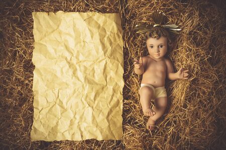 Christmas greeting card, Baby Jesus vintage figurine in his crib and empty paper, copy space.の写真素材