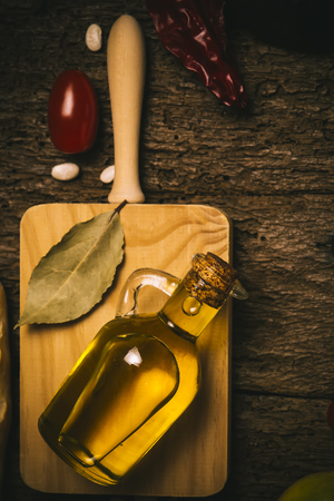 Extra virgin olive oil, laurel and food ingredients on old wooden table. Vertical image.の写真素材