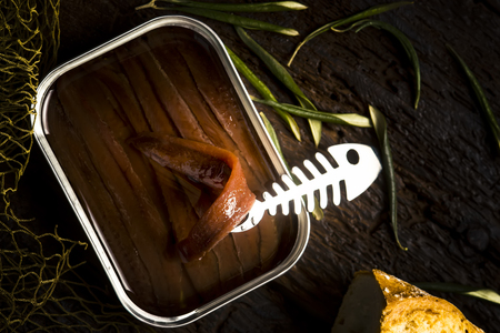Salted anchovy fillets in olive oil tin can.Artisan anchovies from Cantabrian sea salting with olive oil on a rustic wooden tableの写真素材
