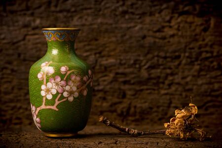 Old cloisonne oriental vase and dead cherry blossom on an old woodenの写真素材