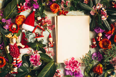 Christmas decorations and natural flowers surrounding an old book with space to write Christmas...