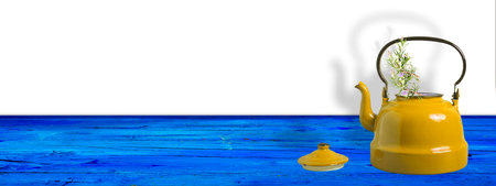 Yellow teapot with sprigs of rosemary on a blue wooden table with blank space for design, panoramic format.の写真素材