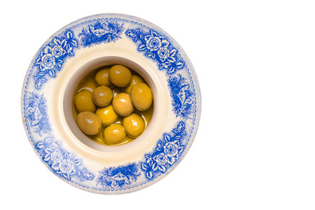 Salted green bone olives with olive oil in a vintage plate isolated on white background.の写真素材