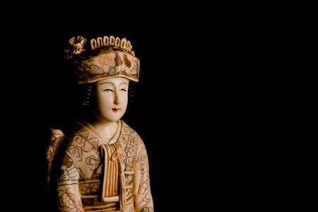 Antique figure of a Japanese geisha portrait in ivory decorated by hand on a black blank background.の写真素材