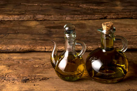 Extra quality cold pressed extra virgin olive oil, two old glass bottles on a rustic wooden backgroundの写真素材