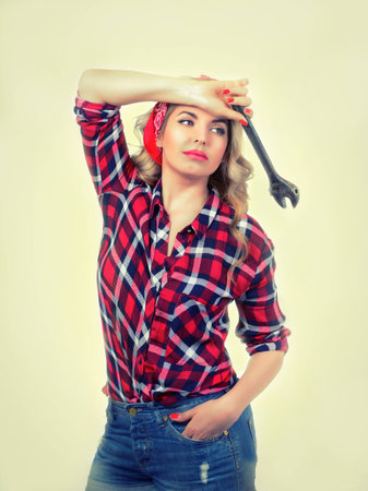 The blonde holds a wrench on a white background