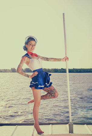 Pin-up girl in a sailor suit with a tattoo is on the shipの写真素材