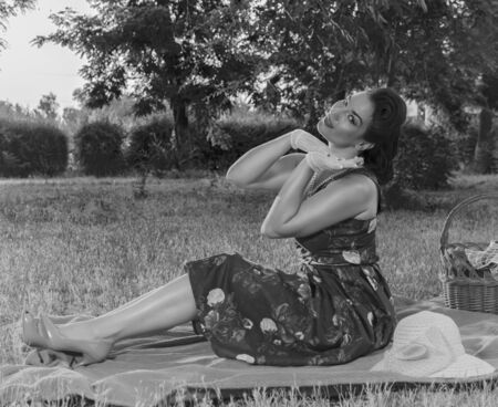 Girl in dress sitting on the grass and looking. Retroの写真素材