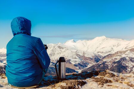 man sits and looks at the snowy mountains