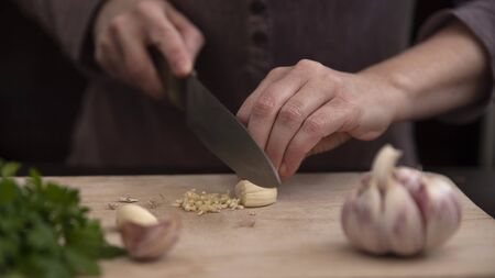 Close-up of the hands of a person cutting garlic with a knifeの写真素材