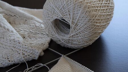 Close-up of a knitted fabric with a ball and needles