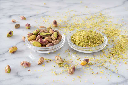 Small pile of pistachios in a saucer, whole shelled and powderedの写真素材
