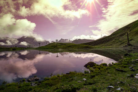 High altitude mountain landscape with the mountain reflected in a lake and a sunsetの写真素材