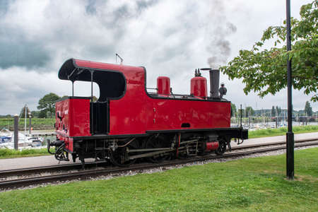 Old red steam train by the sea with boats in Picardie, Franceの写真素材