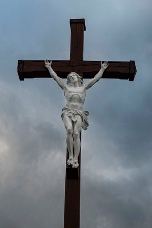 Crucifix of a white stone Jesus Christ on a dark wooden crossの写真素材