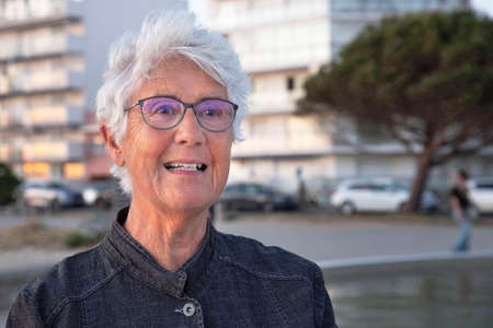 Portrait of an elderly person with glasses and white hair in townの写真素材