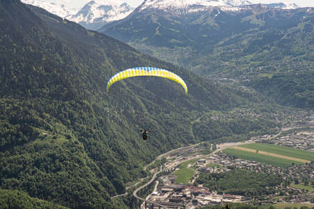 Paragliding over the mountains and a city in the Alps in Franceの写真素材