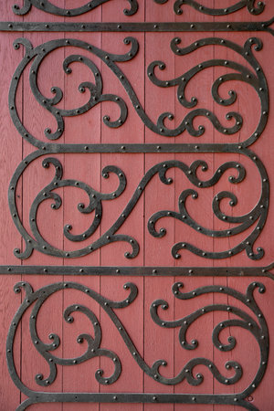 Detail of an old red wooden door with wrought iron decoration in the form of arabesquesの写真素材