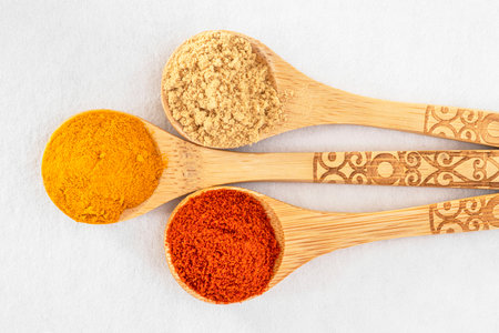 Close-up of colorful spices in wooden spoons on a white backgroundの写真素材