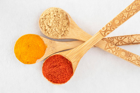 Close-up of colorful spices in wooden spoons on a white backgroundの写真素材