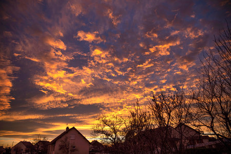 Sunset with clouds on a red sky over a villageの写真素材