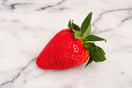 Close-up of a red strawberry on white marbleの写真素材