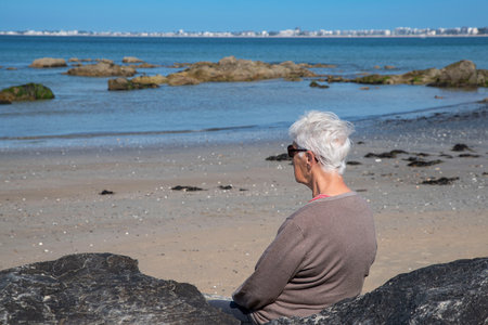 A senior woman on a beach in summer with white hair and sunglassesの写真素材