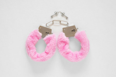 Pair of pink fur handcuffs on a white backgroundの写真素材