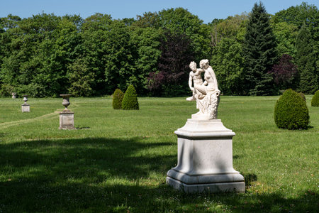 Statue of a couple, a woman and the devil, in a park with lots of vegetation in the Chaalis estate in Franceの写真素材