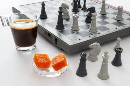 Fruit pastes and coffee in front of a chess game for a moment of relaxation and reflectionの写真素材