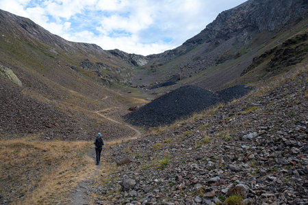 A man hikes in the mountains next to a pile of coal from an old coal mine at Alpe d'Huez in Franceの写真素材
