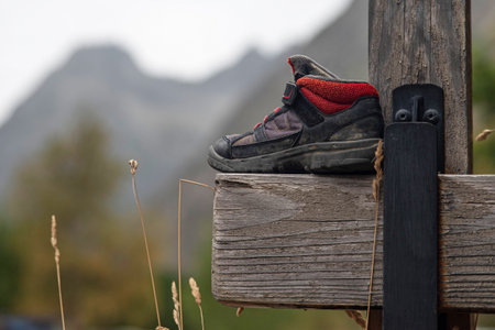 Close-up of a hiking boot on a wooden fence in the mountains in summerの写真素材