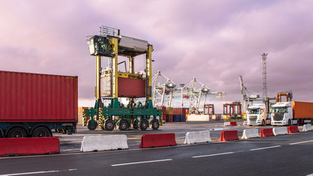 Unloading containers at a commercial port using cranes and trucksの写真素材