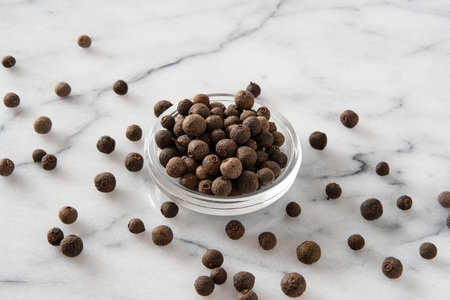 fragrant black pepper in a glass bowl on a marble backgroundの写真素材