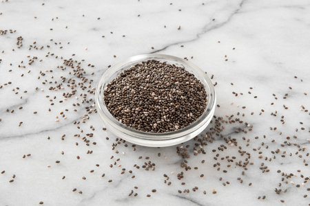 Chia seeds in glass bowl on white marble background, top viewの写真素材