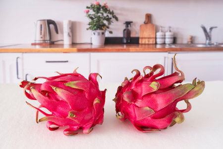 Close-up of whole and cut red dragon fruit on a kitchen tableの写真素材